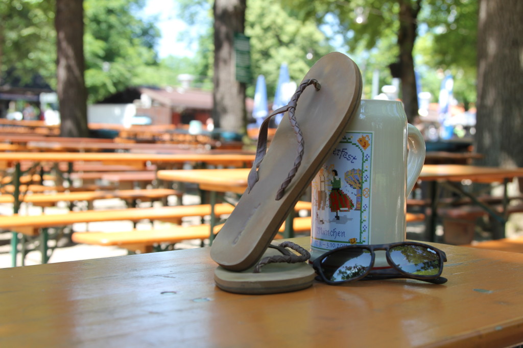 Flip-Flops-mit-Sonnenbrille-und Bierkrug-in-Biergarten
